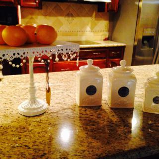 A cozy kitchen scene featuring a fruit stand with oranges and decorative canisters on the countertop.