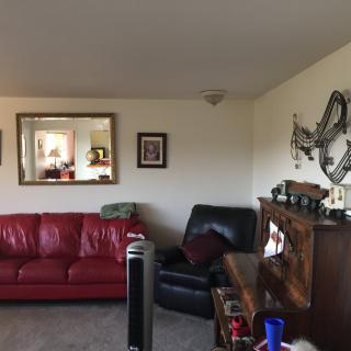 A cozy living room featuring a red sofa, a mirror on the wall, and wooden furniture.