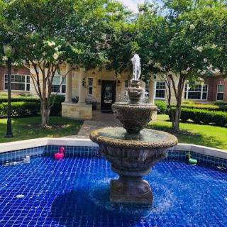A picturesque fountain in a landscaped garden setting outside a building.