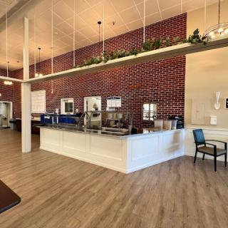 A modern cafe interior featuring a brick wall and wooden flooring, with bright lighting creating an inviting atmosphere.
