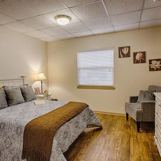 A cozy bedroom with a comfortable bed, bedside lamp, and decorative elements.