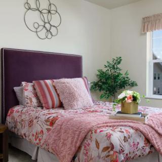 A cozy bedroom with floral bedding and a purple headboard.