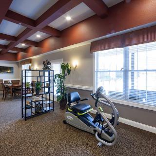 A well-lit indoor space featuring an exercise bike and comfortable seating.