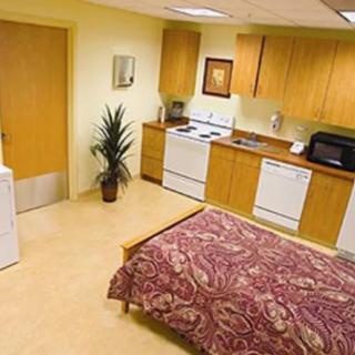 A cozy studio apartment featuring a small kitchen area next to a bed.
