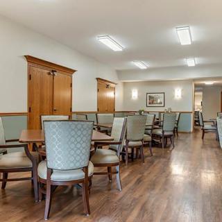 An empty dining room with chairs and tables arranged neatly on a wooden floor.