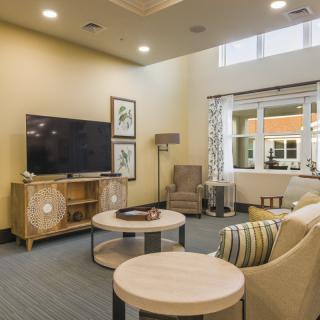 A modern living room with a cozy arrangement featuring a sofa, armchairs, a large flat-screen television, and contemporary decor.
