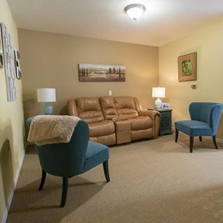 A cozy living room with a brown sofa, two blue chairs, and decorative lamps.