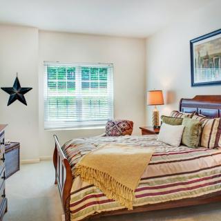 A cozy bedroom featuring a neatly made bed with striped bedding, a bedside lamp, and decorative elements like a star on the wall and a framed picture.
