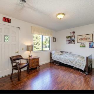 A cozy bedroom with a single bed, wooden flooring, and a window providing natural light.