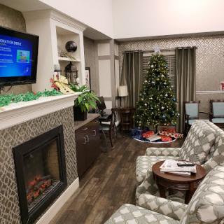 A cozy living room decorated for the holidays with a Christmas tree and a warm fireplace.