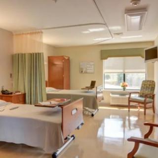 A hospital room with two patient beds and a window providing natural light.