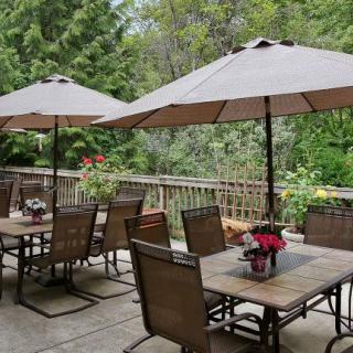 A scenic outdoor patio with tables, chairs, and umbrellas surrounded by lush greenery.