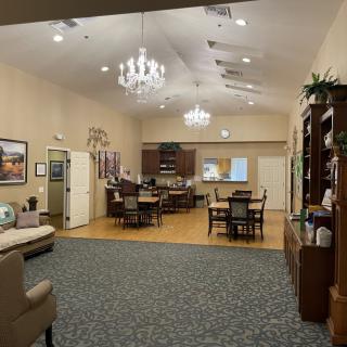 A spacious lounge area with elegant chandeliers, comfortable seating, and various tables arranged for relaxation and socializing.