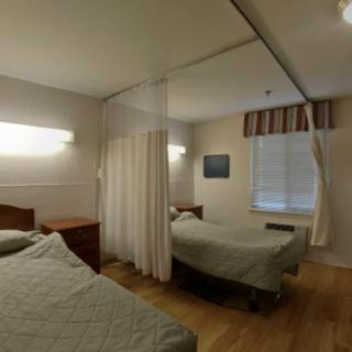 A hospital room with two beds separated by a curtain.