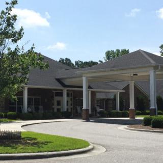 A building entrance with a circular driveway and landscaped surroundings.