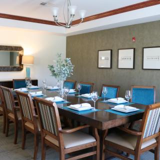 A well-decorated dining room with a large wooden table set for a meal, surrounded by chairs and adorned with elegant decor.