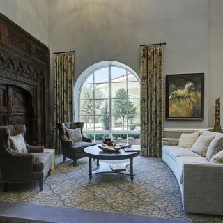 A beautifully designed living room with an arch window, sophisticated furnishings, and elegant decor.