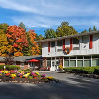 A building surrounded by colorful autumn trees and landscaped gardens on a sunny day.