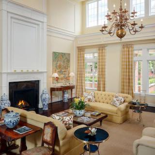 A traditional-style living room with high ceilings, featuring a fireplace and an elegant chandelier.