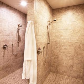 A spacious and modern shower area featuring elegant tile work and a neatly hung white towel.