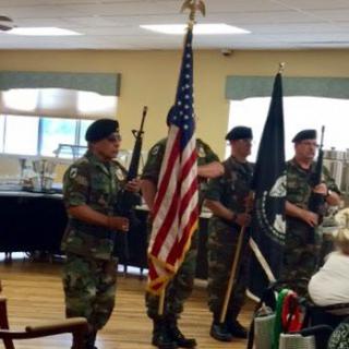 A military honor guard presenting the American flag during an indoor ceremony.