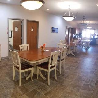 A spacious indoor dining area with tables and chairs, featuring warm lighting and tiled flooring.