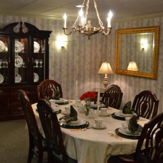 An elegant dining room with a chandelier, set table, and decorative cabinet.