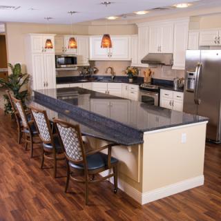 A modern kitchen interior featuring a large island with seating, stainless steel appliances, and wooden flooring.