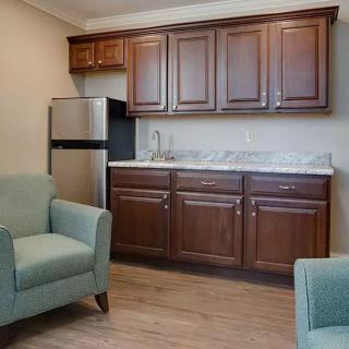 A cozy kitchenette with brown cabinets and two armchairs.