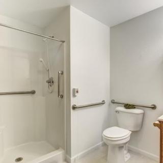 A modern, accessible bathroom with a shower and toilet equipped with grab bars.