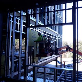 Workers using a lift to install materials on the exterior of a building under construction.