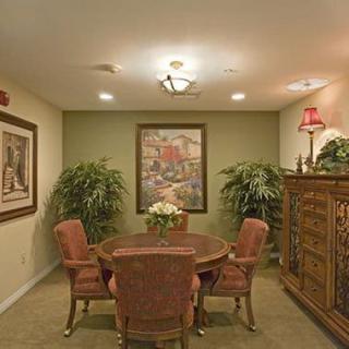 A cozy interior living space with a round dining table surrounded by chairs, adorned with artwork and decorative plants.