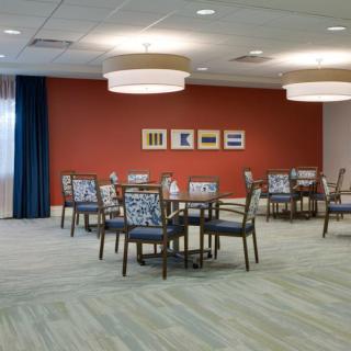 A modern dining area with tables and chairs, featuring contemporary lighting and artwork on a red accent wall.