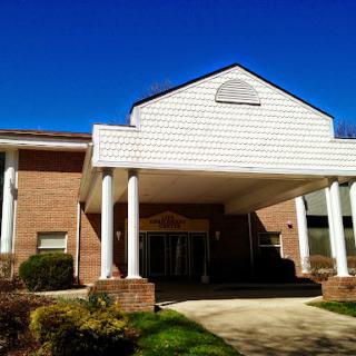 A welcoming front view of a brick building with decorative columns under a clear blue sky.