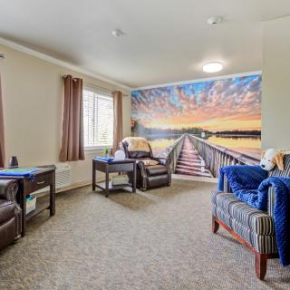 A cozy living room with comfortable seating and a scenic mural on the wall.