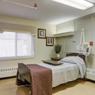 A clean and well-organized hospital room with a patient bed and medical equipment.