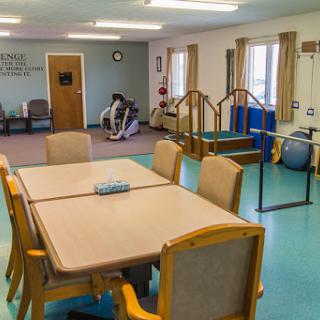 A spacious rehabilitation and therapy room featuring a dining area and various physical therapy equipment.