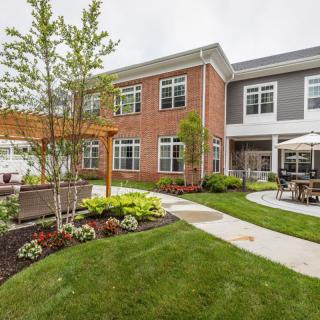 A well-maintained residential building with a landscaped garden and patio area.