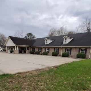 A view of a residential building with a spacious driveway under a cloudy sky.