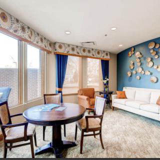 A cozy living room with a round table and chairs, a comfortable sofa, and decorative wall art.