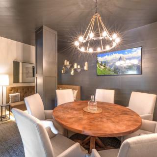 A modern dining room with a round wooden table and elegant chandelier.