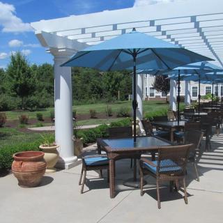 An inviting outdoor patio area with tables and blue umbrellas under a clear sky.