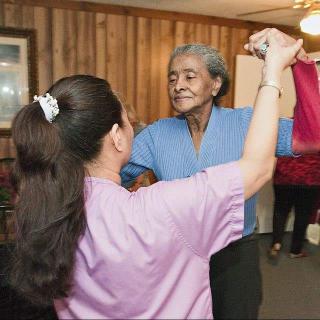 A caregiver dancing with a senior in an indoor setting.