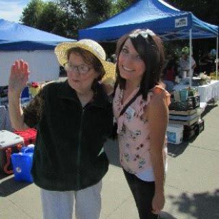 Two people posing together at an outdoor market.