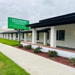 A healthcare clinic with a prominent green sign and manicured landscaping.