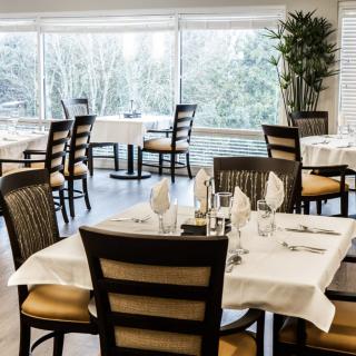 A restaurant dining area with neatly arranged tables and chairs, set for guests.