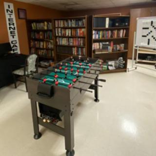 A cozy game room with a foosball table and bookshelves filled with books.