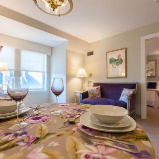 A cozy dining and living room area with a beautifully set table, wine glasses, and a comfortable sofa.