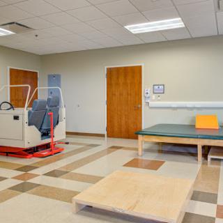 A spacious physical therapy room equipped with exercise equipment and a rehabilitation mat.