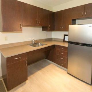 Modern kitchen with wooden cabinets and stainless steel fridge.